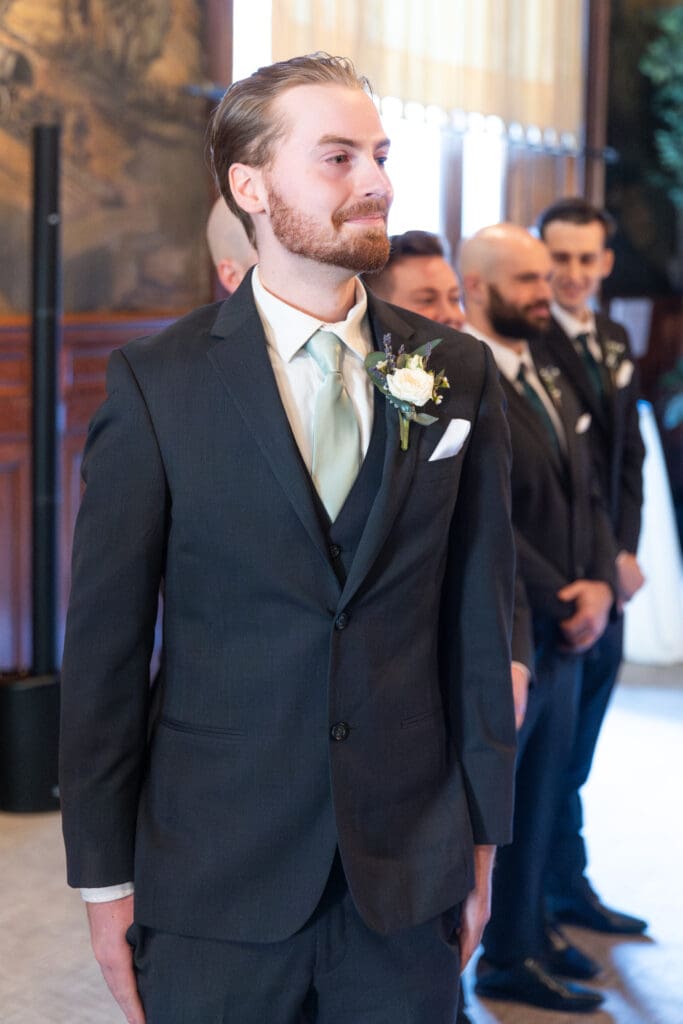 Groom looking at bride walking down aisle